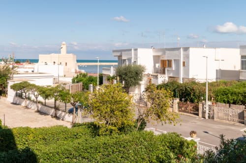 Appartamenti bianchi mediterranei con vista mare a Villanova, Italia, circondati da vegetazione e palme