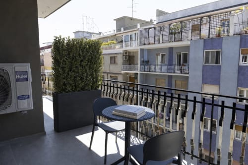 Balcone con tavolo nero, sedie e piante in vaso con vista panoramica sulla città di Bari presso l'hotel Mas Collection