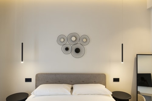 Camera moderna del Mas Collection Bari con letto matrimoniale, arte geometrica a parete, luci a sospensione e arredamento minimalista