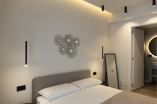Camera moderna di Mas Collection Bari con letto imbottito grigio, lampade a sospensione e decorazioni murali minimaliste
