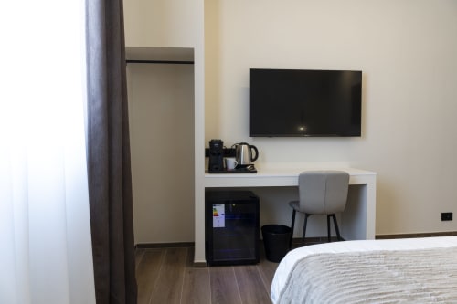 Camera doppia Monfalcone presso Mas Collection Bari: letto, TV a parete, scrivania con sedia, macchina del caffè, minibar, pavimento in legno