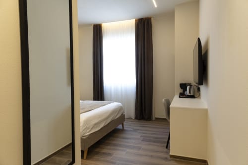 Camera doppia Monfalcone al Mas Collection Hotel di Bari con letto, TV, scrivania e vista città dalla finestra
