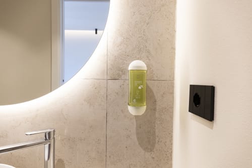 Bagno moderno nella camera Mas Collection Monfalcone a Bari: rivestimenti in travertino, specchio LED e dispenser di sapone verde