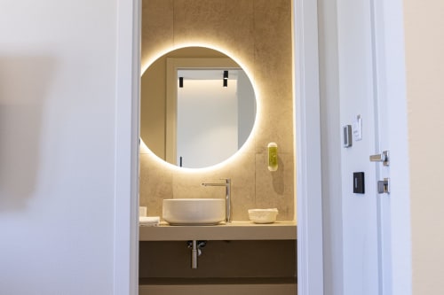 Bagno moderno della collezione Mas hotel di Bari con specchio circolare illuminato e lavabo bianco a ciotola