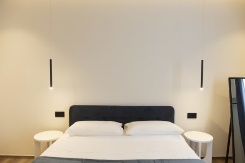 Camera moderna del Mas Collection hotel a Bari con letto matrimoniale, testata scura, cuscini bianchi, illuminazione a sospensione e