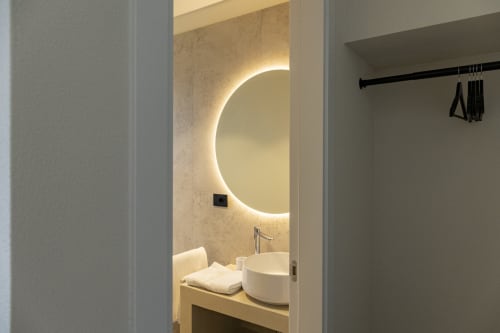 Bagno moderno dell'hotel Mas Collection Bari con specchio rotondo illuminato e lavabo bianco a forma di coppa