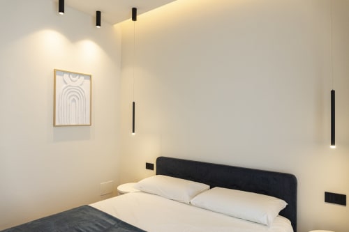 Camera moderna della collezione Mas a Bari con letto matrimoniale, testata nera, lampadari a sospensione e arredamento minimalista