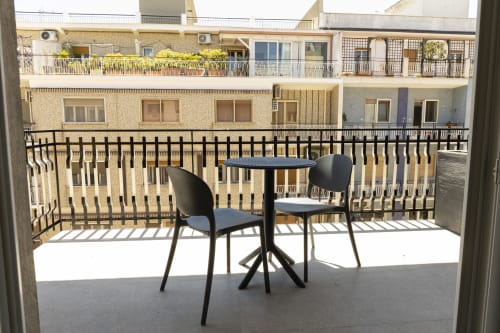 Balcone soleggiato con sedie nere e tavolo rotondo con vista panoramica su Bari all'hotel Mas Collection