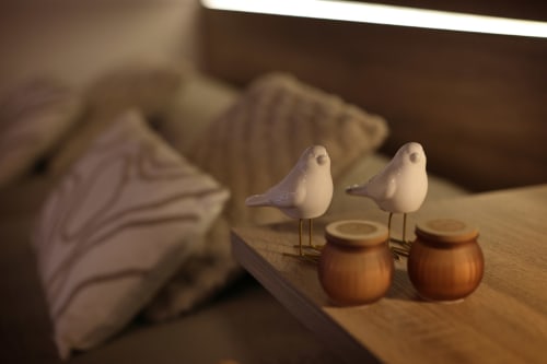 Dos figurillas decorativas de pájaros blancos en repisa de madera con botellas de vidrio ámbar en habitación del hotel Torre de Quintana en Suances