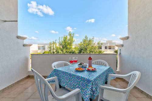 Zona pranzo all'aperto presso Il Porticciolo Vacanze a Villanova con tavolo, sedie, vino e antipasti con vista sui giardini