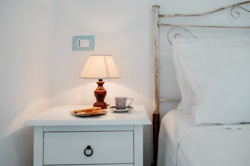 Cozy camera da letto con comodino, lampada, tazza di tè e pasticcini all'appartamento Il Porticciolo Vacanze a Villanova