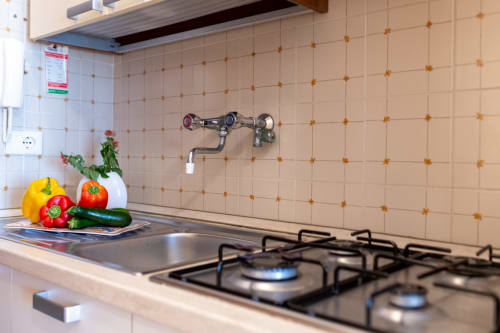 Angolo cucina di Il Porticcolo con fornello a gas, verdure fresche e rivestimento piastrellato nell'appartamento di Villanova