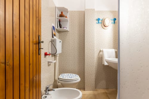 Moderno bagno dell'appartamento Il Porticicolo Vacanze a Villanova con lavabo bianco, WC con motivi azzurri, pareti piastrellate e