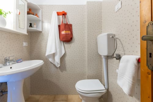 Bagno compatto a Il Porticicolo Vacanze con sanitari bianchi, pareti piastrellate beige e servizi essenziali a Villanova
