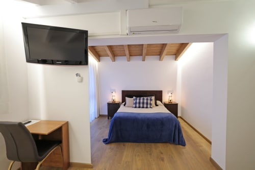Moderna habitación doble en Torre de Quintana, Suances, con ropa de cama azul, TV de pantalla plana, vigas de madera y vistas al jardín