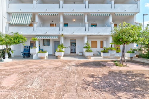 Cortile dell'hotel Il Porticicolo Vacanze a Villanova con appartamenti bianchi, piante verdi e zona patio in cotto