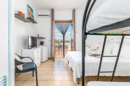 Moderno monolocale a Il Porticciolo Vacanze con letti a castello, TV, angolo cottura e balcone con vista sul giardino a Villanova