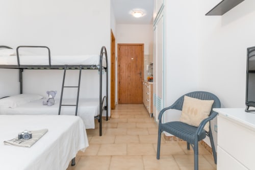 Ampia camera da letto in appartamento a Il Porticciollo Vacanze con letti a castello, poltrona e comfort moderni a Villanova, Italia