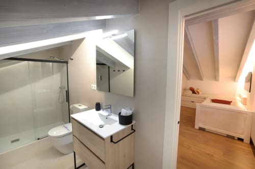 Baño moderno del hotel Torre de Quintana en Suances con tocador, espejo iluminado, ducha abierta y inodoro