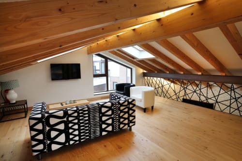 Acogedor loft en ático del hotel Torre de Quintana en Suances con vigas de madera vista, muebles con patrones geométricos y