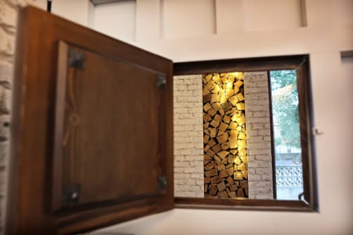 Vitrinas de madera con leña apilada e iluminación cálida en el hotel Torre de Quintana en Suances