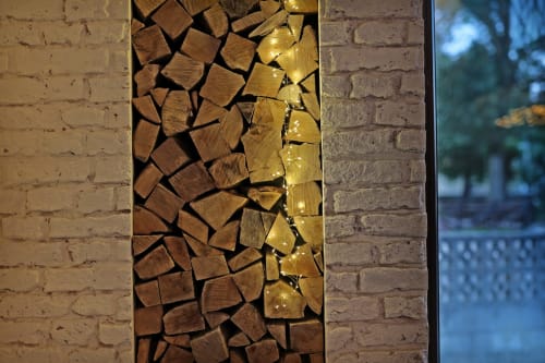 Troncos de madera iluminados con luces cálidas en la entrada del hotel Torre de Quintana, Suances
