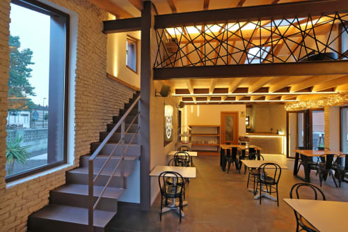 Elegante salón del Hotel Torre de Quintana en Suances con escalera, mesas de comedor e iluminación cálida