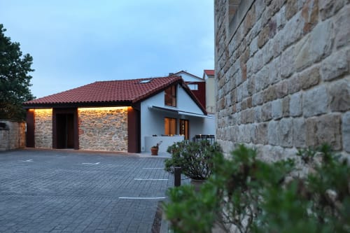 Entrada del hotel Torre de Quintana en Suances con fachada de piedra, tejado de tejas rojas y arquitectura moderna iluminada al atardecer
