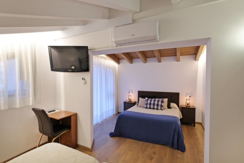 Habitación moderna del hotel Torre de Quintana en Suances con cama, TV, escritorio y techo de vigas de madera