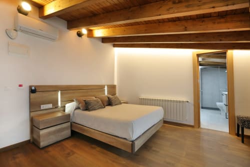 Habitación moderna en el hotel Torre de Quintana de Suances con vigas de madera, cama contemporánea y baño en suite