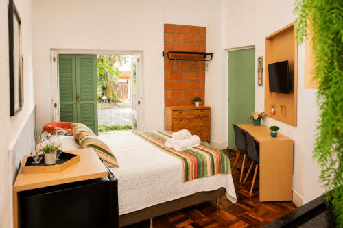 Quarto tipo loft em Veneto, Maringá, com vista para o jardim, móveis em madeira, detalhes verdes e comodidades modernas