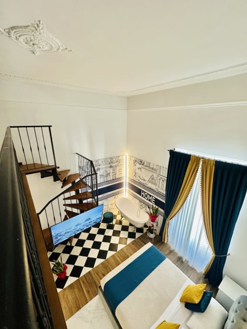 Suite deluxe quadrupla St Mary Major Loft Roma con scala a spirale, pavimento a scacchi bianco e nero, e finestre con vista sulla città