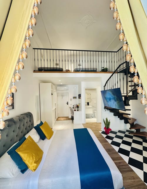 Camera Quadrupla Deluxe al St Mary Major Loft Roma con letto matrimoniale, dettagli blu, soppalco in mezzanino, scale a chiocciola e vista sulla città