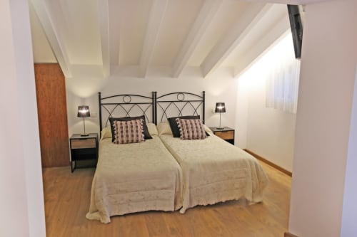 Dos camas gemelas con cabeceras metálicas en la luminosa Habitación Familiar del hotel Torre de Quintana en Suances, con vigas de madera