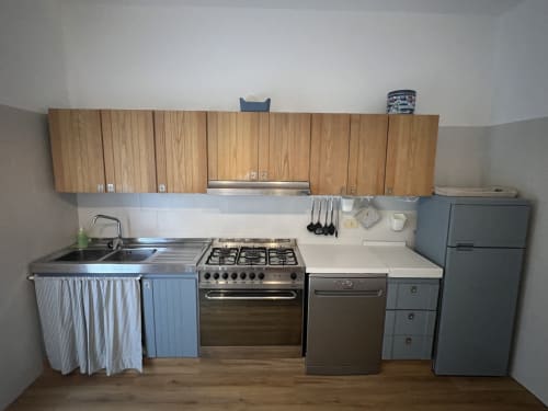 Cucina vintage con mobili in legno, fornello a gas e elettrodomestici in acciaio inox nell'appartamento La Casetta Vintage a Selva