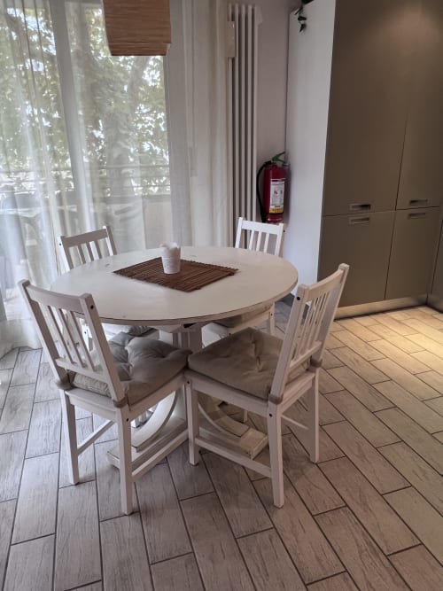 Luminosa zona living dell'appartamento Selva Marina con tavolo rotondo bianco, sedie bianche e vista giardino dalle finestre
