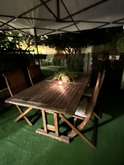 Area esterna di Selva Marina Casa Vacanze a Riccione con tavolo in legno, sedie ombreggiate su prato verde