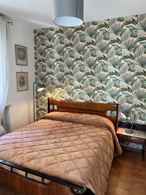 Camera da letto di Selva Marina Casa Vacanze a Riccione con carta da parati a foglie tropicali, letto in legno e biancheria beige