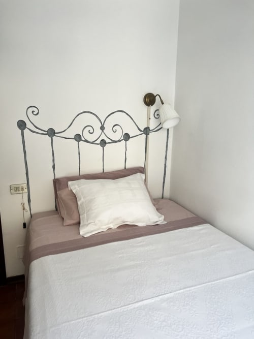 Letto in stile vintage con testata in ferro battuto ornato, biancheria bianca e runner malva presso Selva Marina Casa Vacanze a Riccione