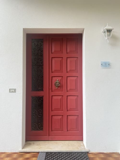 Porta d'ingresso rossa con pannelli laterali ornamentali dell'appartamento Selva Marina Casa Vacanze a Riccione