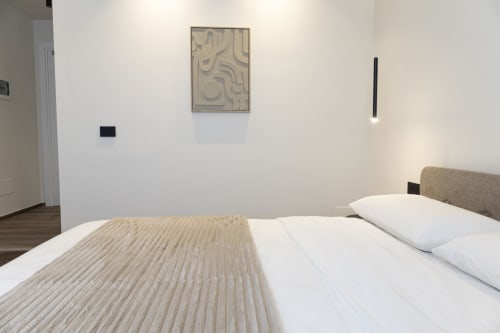 Modern bedroom at Mas Collection hotel in Bari with bed, white pillows, and minimalist wall art