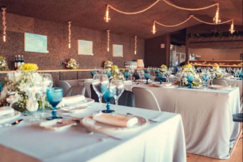 Elegante salão de banquetes no Charm Nature BnB em Azóia com mesas brancas, acentos azuis, arranjos florais e ambiente acolhedor