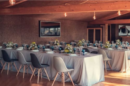 Elegante salão de banquetes do Charm Nature BnB em Azóia com mesas redondas, toalhas brancas, cadeiras azuis e arranjos florais