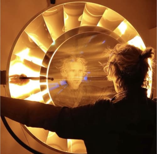 Persona observando una instalación de arte circular iluminada en Casale Artemisia, Capalbio