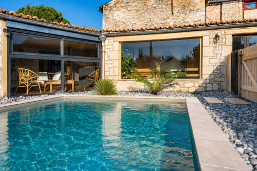 Cottage Maison Azur au Clos Divin avec piscine turquoise, terrasse en pierre et baies vitrées modernes dominant les jardins