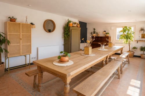 Salle à manger spacieuse du gîte Le Clos Divin avec table en bois, bancs, plantes et lumière naturelle