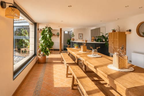 Salle à manger lumineuse avec tables et bancs en bois au gîte Le Clos Divin, vue sur terrasse et piscine