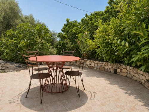 Table à manger en terre cuite avec chaises sur la terrasse, entourée de verdure luxuriante à la villa Santa Reparata à L'Île-Rousse, Corse