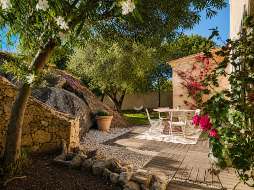 Terrasse de jardin sereine avec mobilier blanc, vignes fleuries et arbres d'ombrage à la villa Santa Reparata à L'Île-Rousse