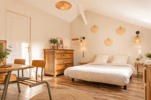 Chambre spacieuse du gîte Maison Azur avec mobilier en bois, luminaires suspendus tressés et literie blanche moderne au Clos Divin
